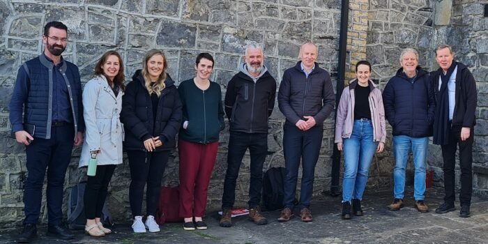 A photograph showing nine people standing in a row outside a community building taken at the community sustainability connected launch Ballina Mayo